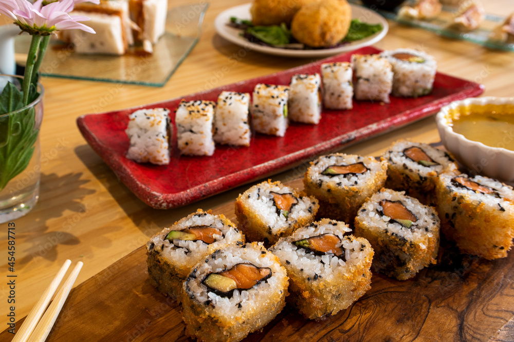 sushi uramaki roll of salmon with avocado in tempuras with sauces and more uramaki with chopsticks to eat sushi uramaki roll of salmon with avocado in tempuras with sauces and more uramaki with chopsticks to eat