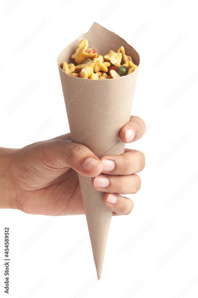 Crunchy plane salty Golden Mixture Indian namkeen (snacks) in a brown paper cone holding in hand isolated over white, Indian spicy snacks (Namkeen) Crunchy plane salty Golden Mixture Indian namkeen (snacks) in a brown paper cone holding in hand isolated over white, Indian spicy snacks (Namkeen)