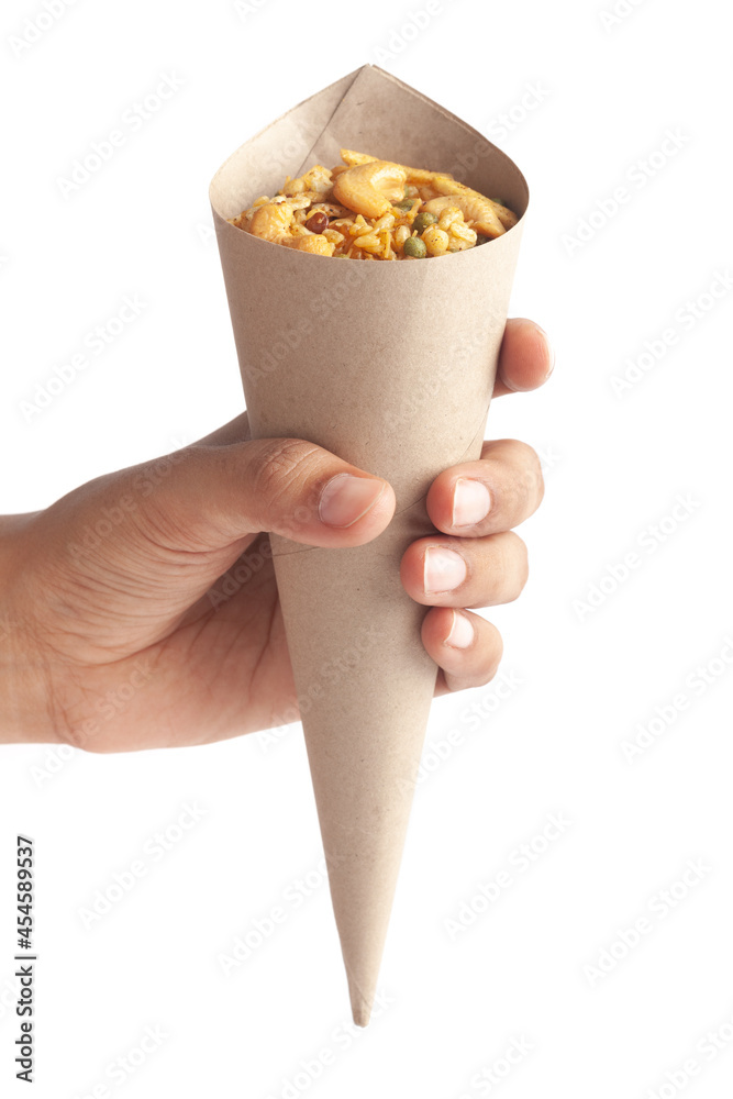 Close-Up of Crunchy Rich Spicy Kaju Mixture Indian namkeen (snacks) in a brown paper cone holding in hand isolated over white, Indian spicy snacks (Namkeen) Close-Up of Crunchy Rich Spicy Kaju Mixture Indian namkeen (snacks) in a brown paper cone holding in hand isolated over white, Indian spicy snacks (Namkeen)