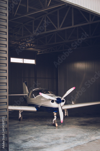 Small white private jet parked in the hangar