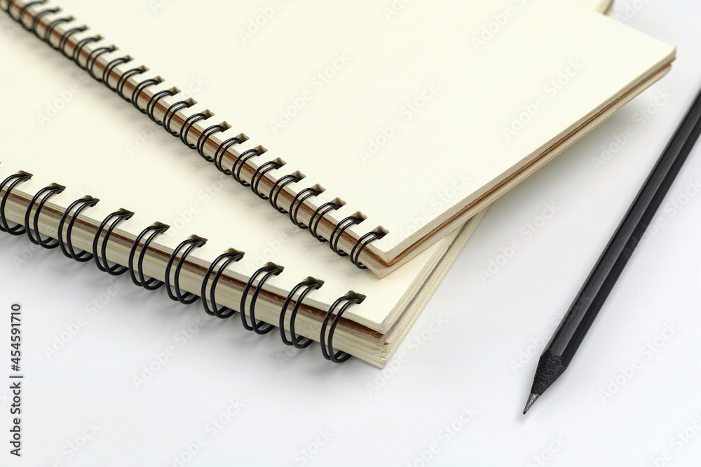 Close up spiral notebook and black pencil on white background for mockup blank template Close up spiral notebook and black pencil on white background for mockup blank template
