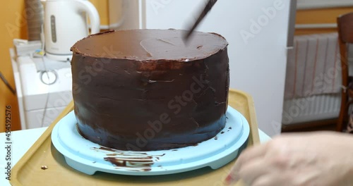 Confectioner woman is smearing cream on sides of cake using spatula, closeup view. culinary, baking and cooking food concept, home cooking