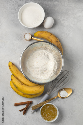 Ingredients for banana bread in bowls on light gray background top view