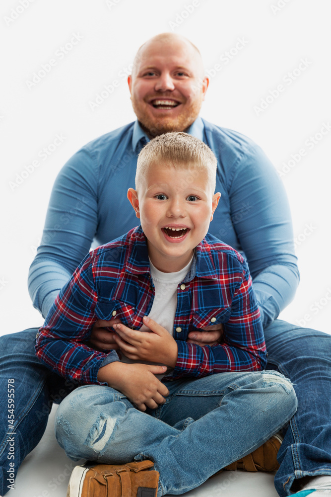 Dad and son, 6-7 years old, hug and laugh. Happy family relationships, love and tenderness. White background. Vertical. Dad and son, 6-7 years old, hug and laugh. Happy family relationships, love and tenderness. White background. Vertical.