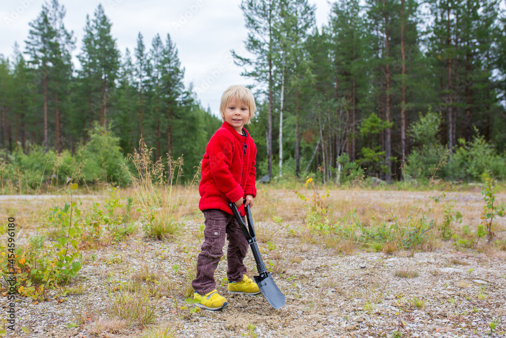 Cute child, digging a hole, cleaning after himself on a wild camping Cute child, digging a hole, cleaning after himself on a wild camping