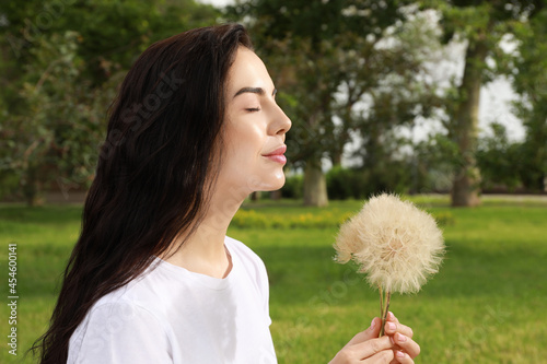 Beautiful young woman with large dandelions in park. Allergy free concept