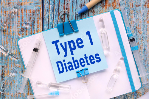 diabetes type 1. the sticker is attached to the notebook with a clerical clip. notebook on a wooden table in blue photo