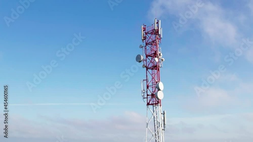 Radio communication base station against a background of blue sky and clouds. Roll camera movement. Aerial view