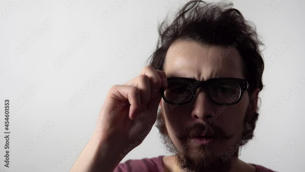 Closeup view of man wearing glasses and trying to see something frowning his eyebrows. Portrait of bearded person who is perplexed and do not understand something. Puzzled hipster on white background. Closeup view of man wearing glasses and trying to see something frowning his eyebrows. Portrait of bearded person who is perplexed and do not understand something. Puzzled hipster on white background.