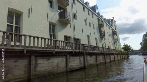 Riding in a boat along houses in Amsterdam on a canal in summer on sunny day.
 photo