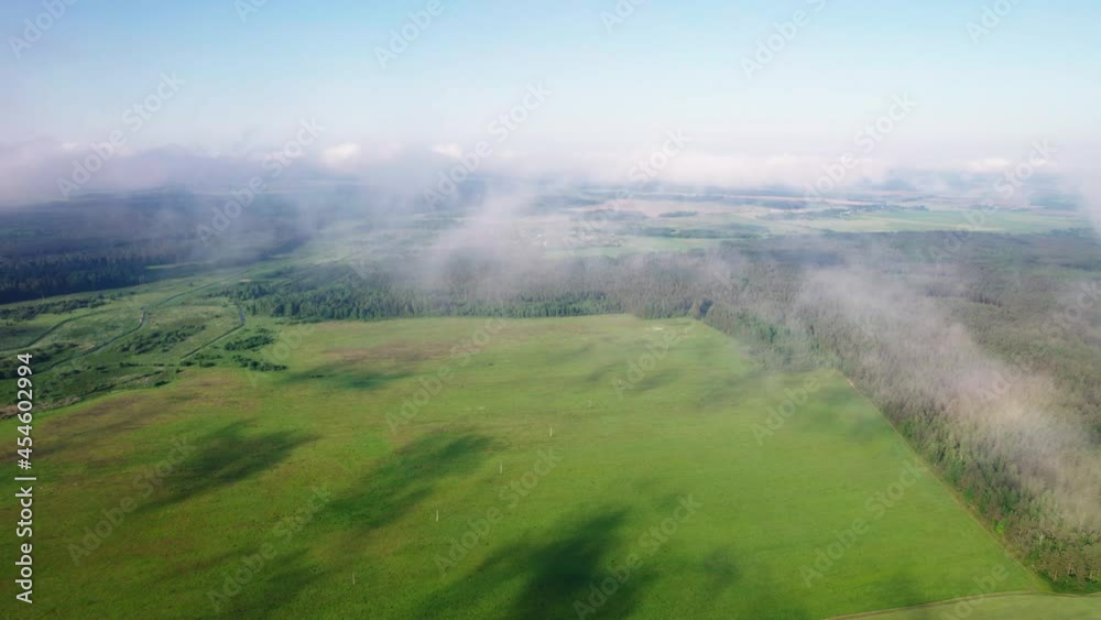 Aerial: picturesque countryside from the sky under white feathery clouds. Sunny plain with fields and forests from a bird's-eye view Aerial: picturesque countryside from the sky under white feathery clouds. Sunny plain with fields and forests from a bird's-eye view