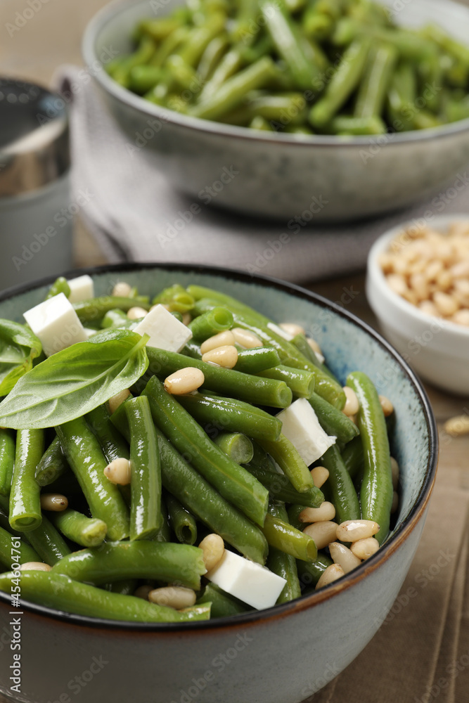 Delicious salad with green beans, pine nuts and cheese on table, closeup Delicious salad with green beans, pine nuts and cheese on table, closeup