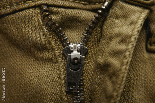 Metal zipper on denim texture, closeup or macro view. Fastener on jeans.  photo
