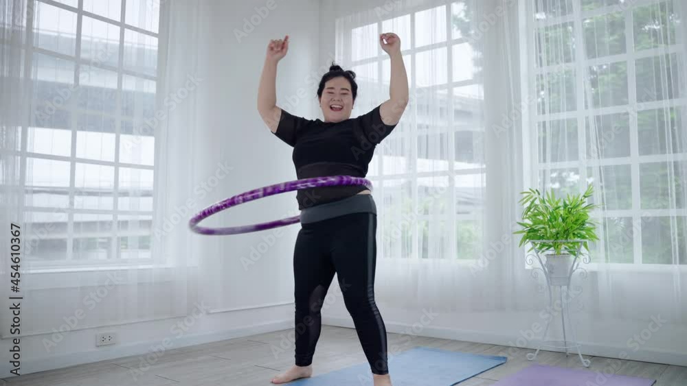 Fat Asian woman playing hula hoop to lose weight cheerfully in her room. health and weight loss concept Fat Asian woman playing hula hoop to lose weight cheerfully in her room. health and weight loss concept
