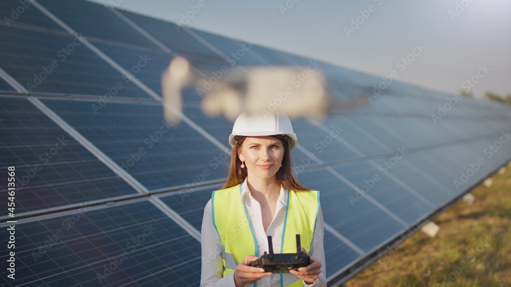 Portrait of a female engineer operating a drone on the background of a solar power plant. Solar panel array installation. Technologies and ecology. Sunsets. Portrait of a female engineer operating a drone on the background of a solar power plant. Solar panel array installation. Technologies and ecology. Sunsets.