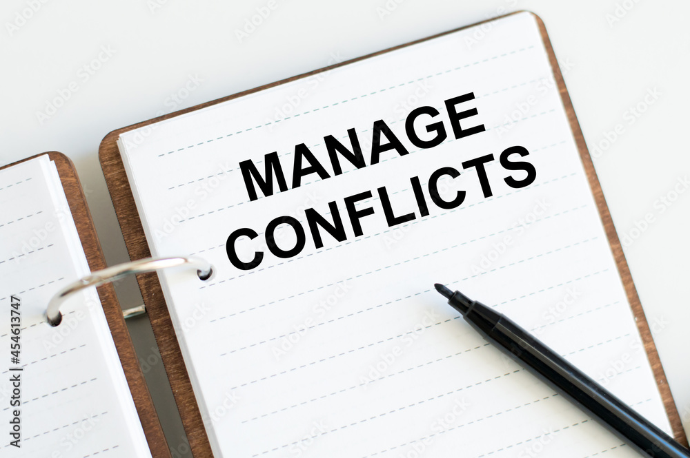 Managing Conflicts inscription on notepad on white background near black marker, business conceptual Managing Conflicts inscription on notepad on white background near black marker, business conceptual