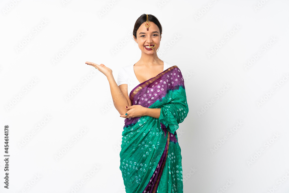 Young indian woman isolated on white background holding copyspace imaginary on the palm to insert an ad
