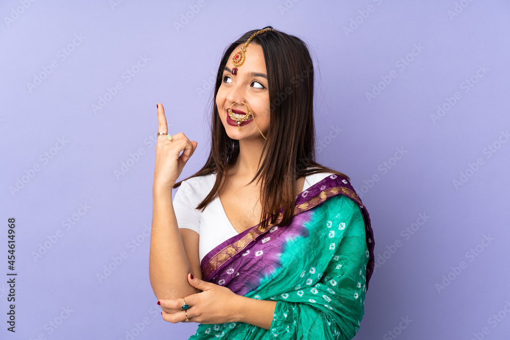 Young Indian woman isolated on purple background pointing up a great idea Young Indian woman isolated on purple background pointing up a great idea
