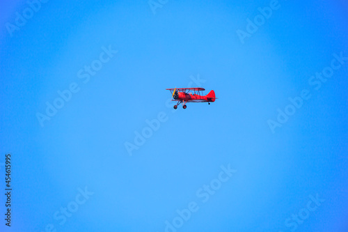 Old red airplane flying in a blue sky