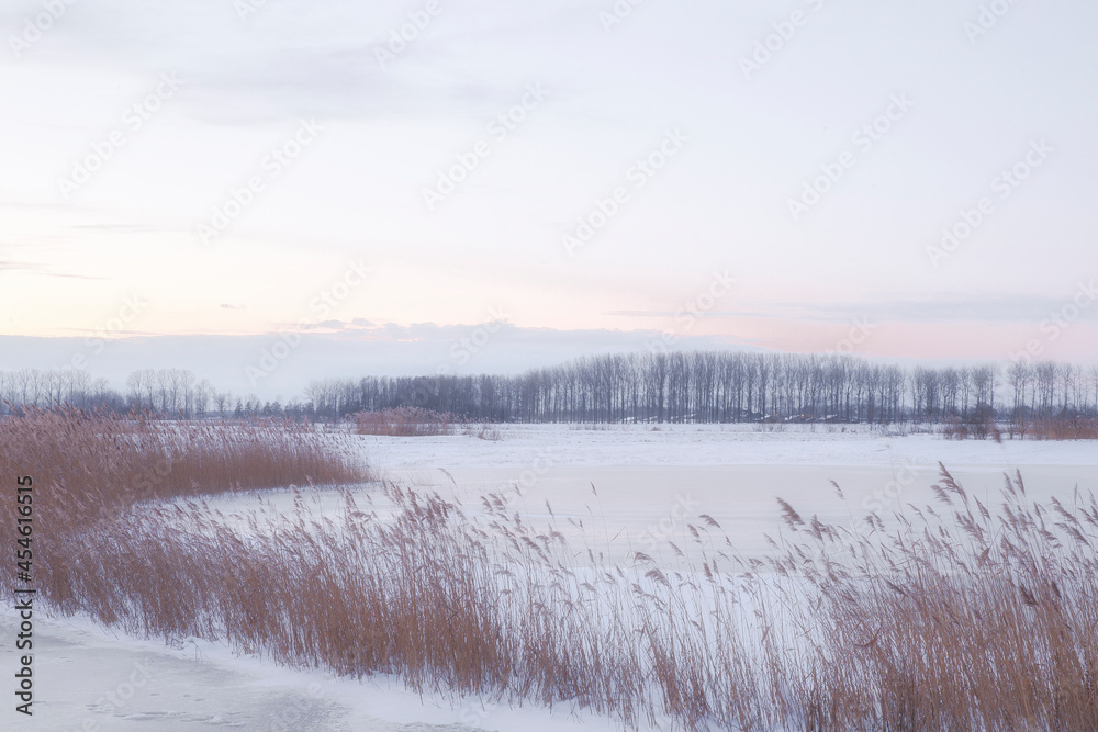 Beautiful winter landscape at sunset with fog and snow covering farmland and river in the Netherlands beautiful colors in nature