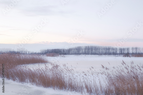 Beautiful winter landscape at sunset with fog and snow covering farmland and river in the Netherlands beautiful colors in nature