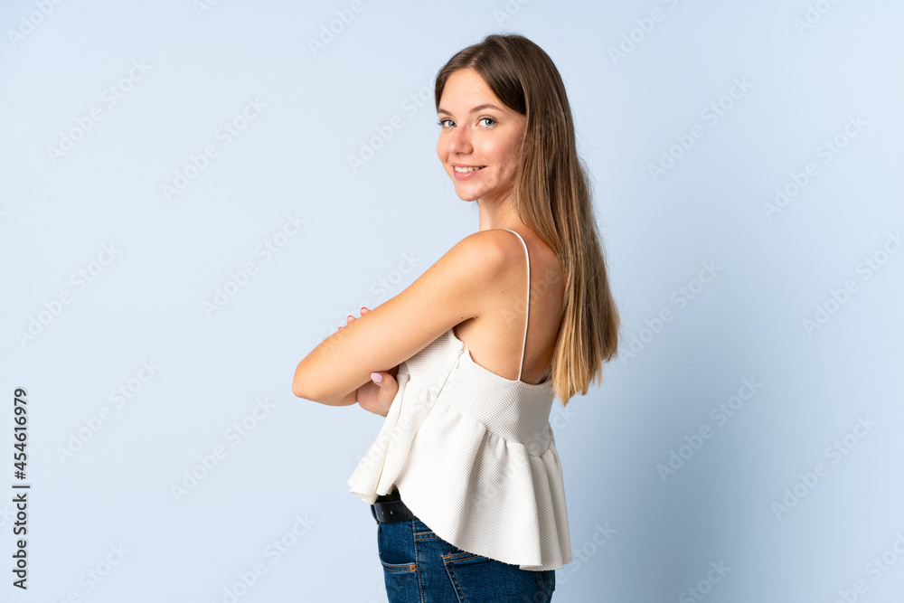 Young Lithuanian woman isolated on blue background with arms crossed and happy Young Lithuanian woman isolated on blue background with arms crossed and happy