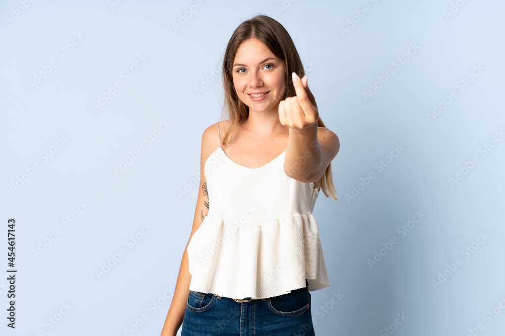 Young Lithuanian woman isolated on blue background doing coming gesture Young Lithuanian woman isolated on blue background doing coming gesture