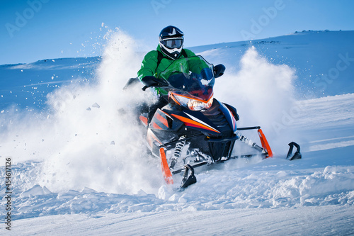 Snowmobile riding with fun in deep snow powder during backcountry tour. Extreme sport adventure, outdoor activity during winter holiday on ski mountain resort