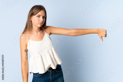 Young Lithuanian woman isolated on blue background showing thumb down with negative expression