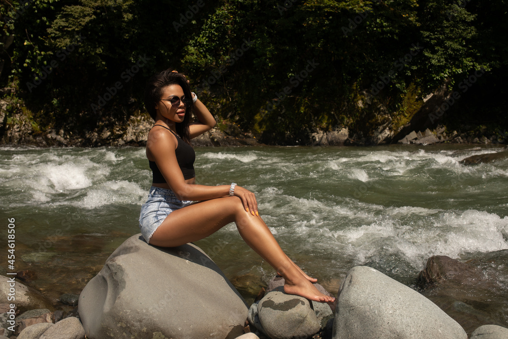 Young black woman tourist relaxes in river.