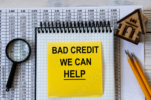 BAD CREDIT WE CAN HELP - words in a notebook against the background of a wooden house, pencils and a magnifying glass photo