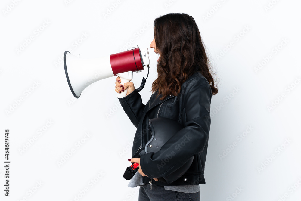 Young woman holding a motorcycle helmet over isolated white background shouting through a megaphone Young woman holding a motorcycle helmet over isolated white background shouting through a megaphone