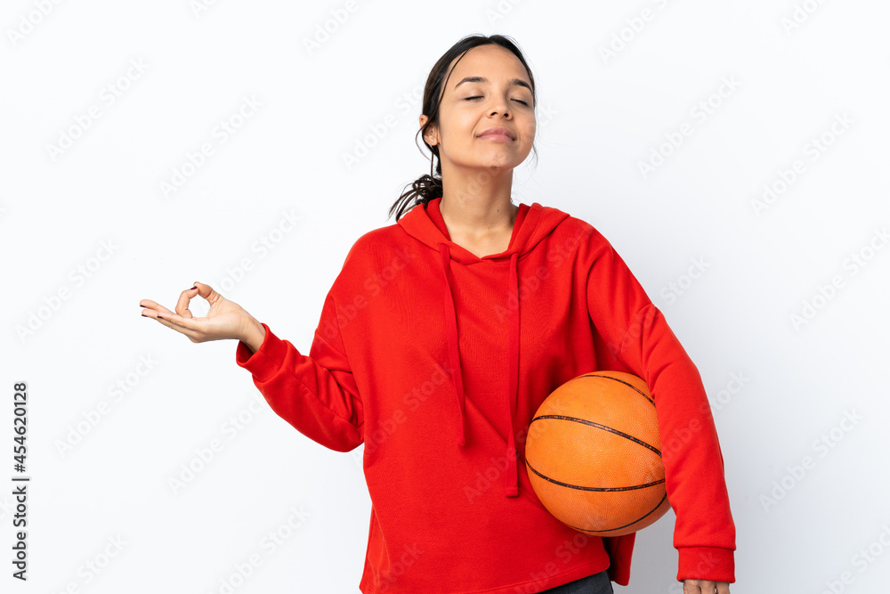 Young woman playing basketball over isolated white background in zen pose