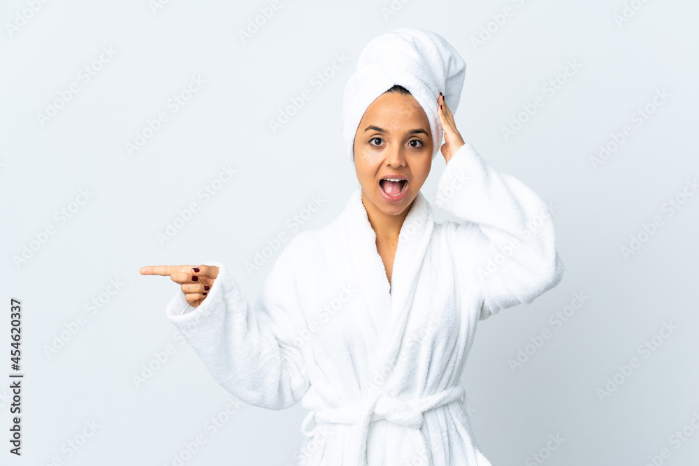 Young woman in bathrobe over isolated white background surprised and pointing finger to the side Young woman in bathrobe over isolated white background surprised and pointing finger to the side