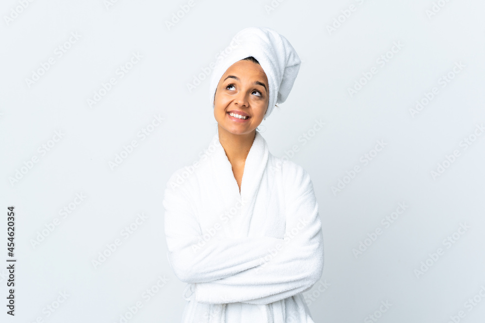 Young woman in bathrobe over isolated white background looking up while smiling Young woman in bathrobe over isolated white background looking up while smiling
