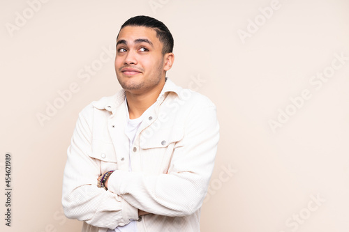 Asian handsome man over isolated background making doubts gesture while lifting the shoulders