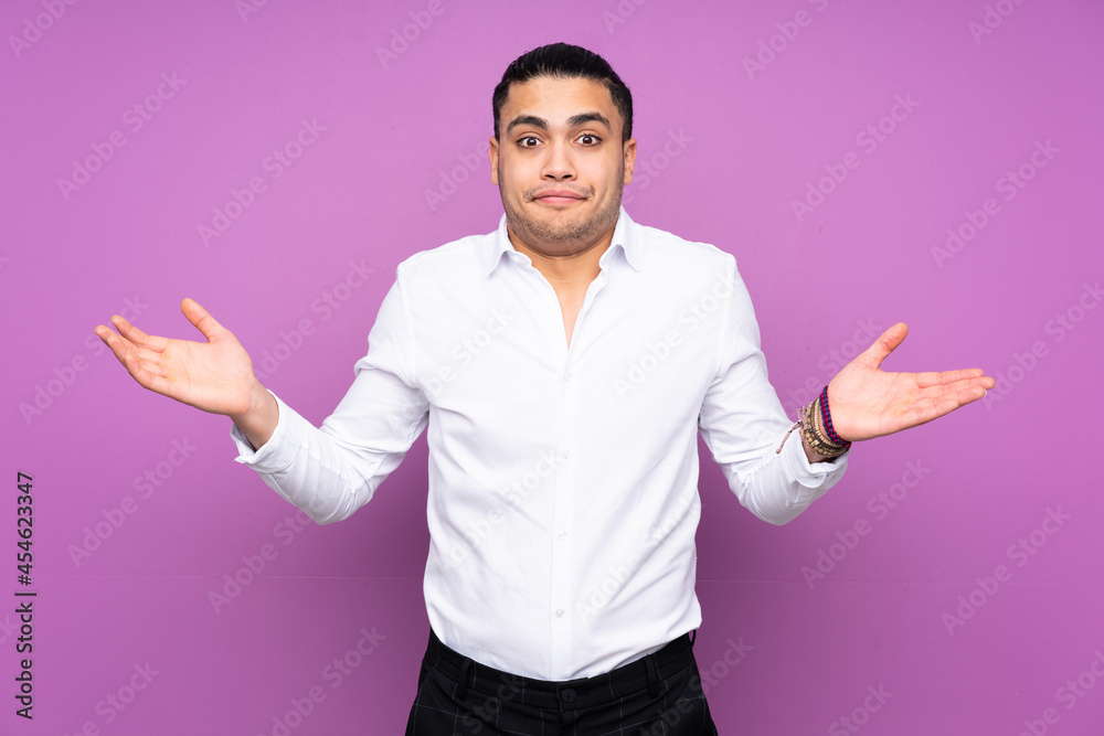 Asian handsome man isolated on blue background having doubts while raising hands Asian handsome man isolated on blue background having doubts while raising hands