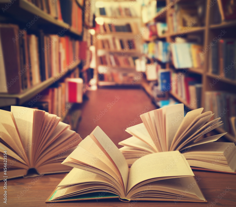 Fototapeta premium Open books on wooden table in library