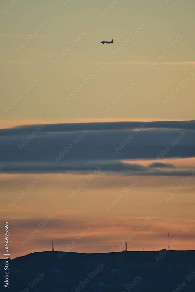 Fototapeta premium Beautiful early morning view of airplane passing above Howth seen from Blackrock, Dublin, Ireland before sunrise. Soft and selective focus