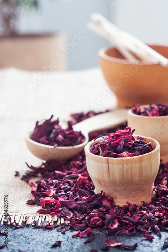 Dry hibiscus tea in wooden spoon and small cups