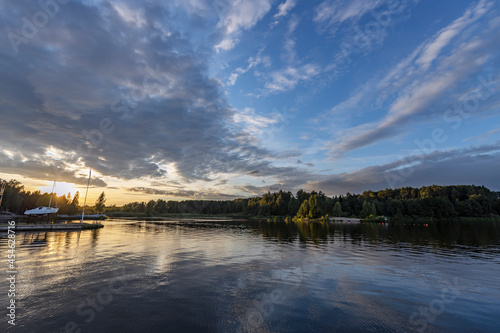 Picturesque sunset on the river with clouds. The dramatic evening sky is reflected in the river.
