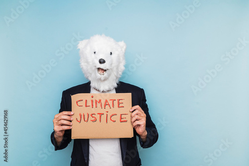 Fotografie, Obraz Man in a polar bear mask holding a sign that says climate justice