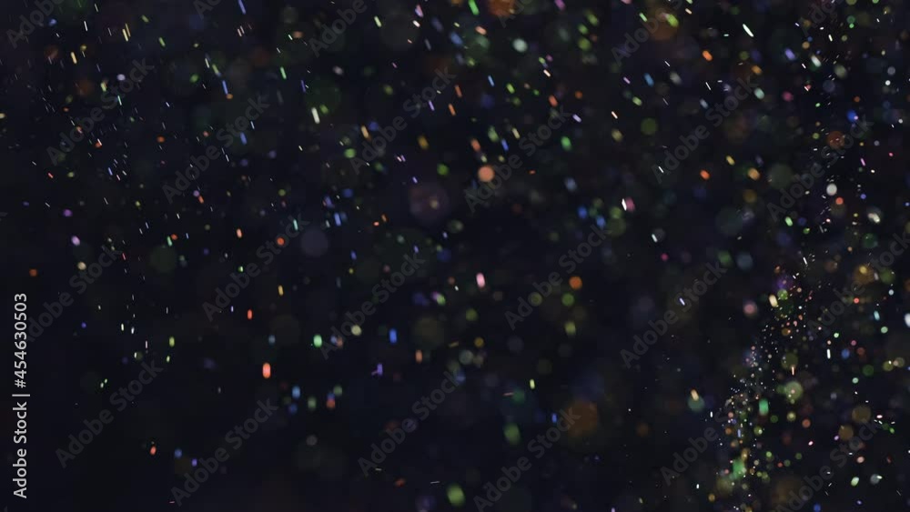 The sparkling particles floating on the dark background. slow motion