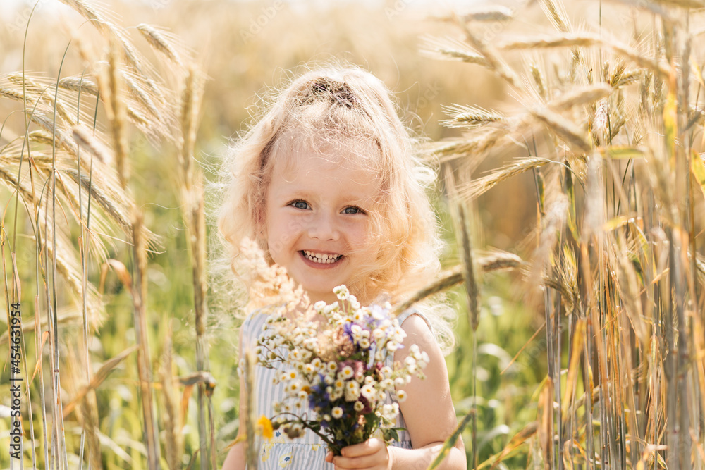 Little cute blonde girl with a bouquet of wildflowers in nature in the summer Little cute blonde girl with a bouquet of wildflowers in nature in the summer