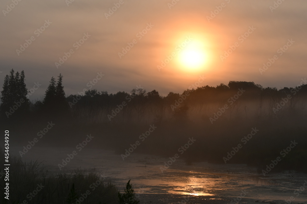 Sunrise over river on a foggy autumn morning 