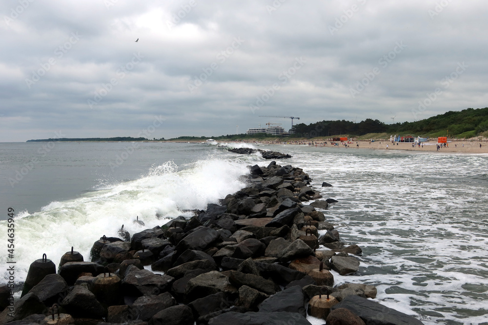 Strong sea ​​waves crashing on the breakwater. Cloudy summer day. Darlowo, Poland