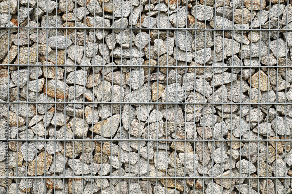 Garden architecture. A wall made of gabions, next to it a bench and a garbage can.