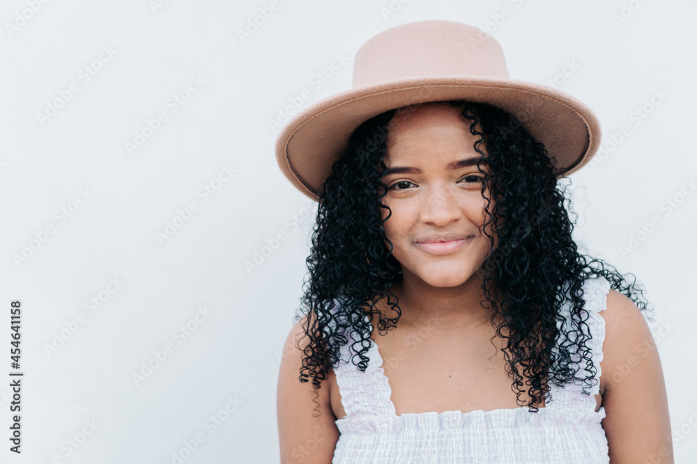 Portrait of a beautiful young woman with a hat on the city street on a white wall background. Portrait of a beautiful young woman with a hat on the city street on a white wall background.