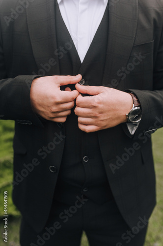 Stylish man, businessman, boss buttons up the buttons on a black suit, jacket with his hands. Business photography.