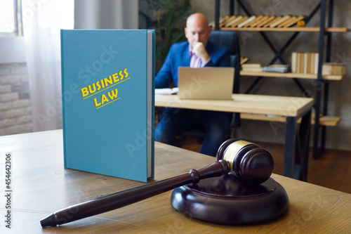 Lawyer holds BUSINESS LAW book. Commercial law regulates corporate contracts, hiring practices, and the manufacture and sales of consumer goods photo